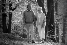 senior couple walking through the woods hand-in-hand in the Fall talking about what legacy they'd like to leave.