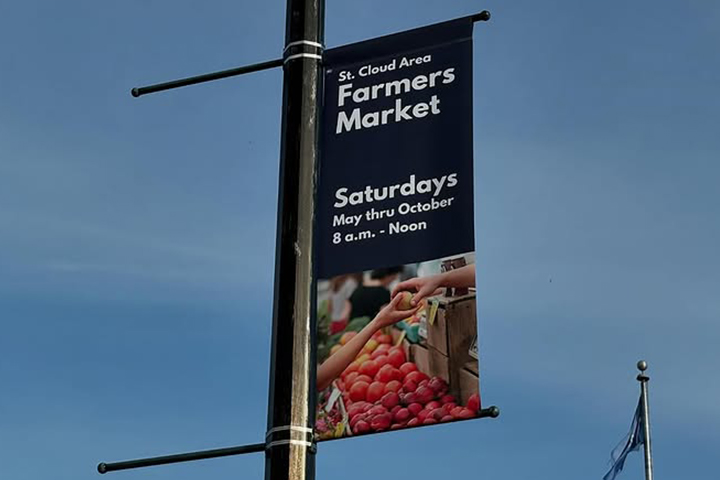 Banner on a pole advertising St. Cloud Area Farmers Market, Saturdays, May-October, 8 a.m.–noon.
