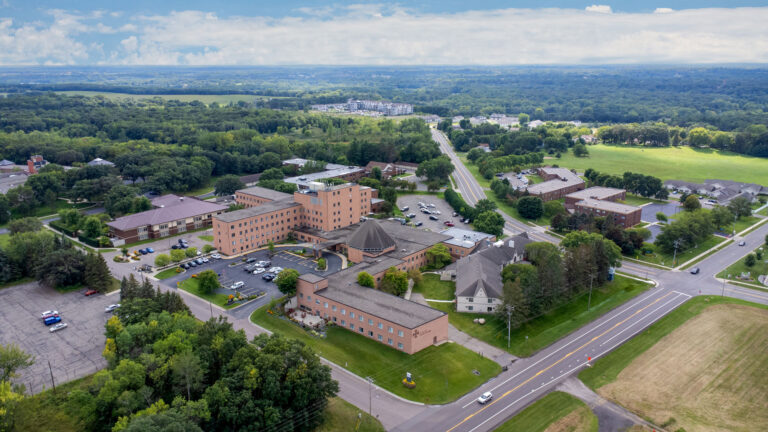 Aerial view of a large complex surrounded by trees and roads in a rural landscape.