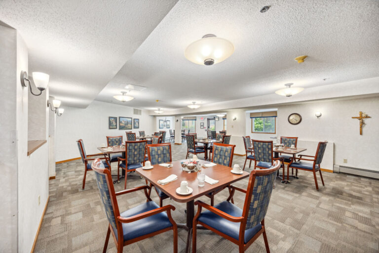 Benedict Court Dining: A bright room with wooden tables, chairs, place settings, wall art, and overhead lighting.