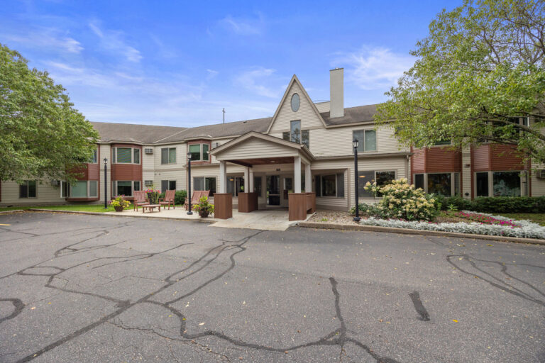Front view of a two-story residential building with trees, showcasing the central Benedict Court entrance.
