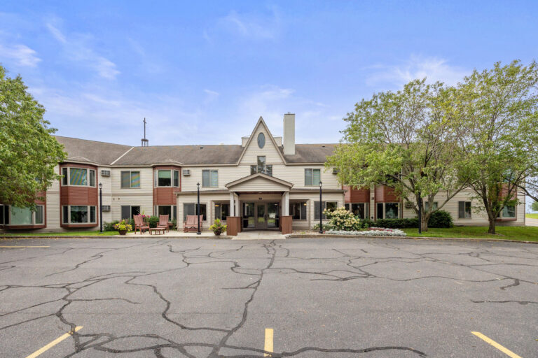 Front view of a two-story residential building with trees, showcasing the central Benedict Court entrance.