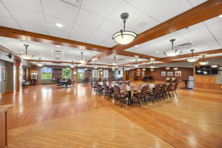 The Bonn Great Room boasts round tables, chairs, and large windows offering natural light and outdoor views.
