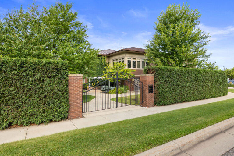 Gated entrance to Rosies Garden, surrounded by lush greenery and a pathway leading to a building.