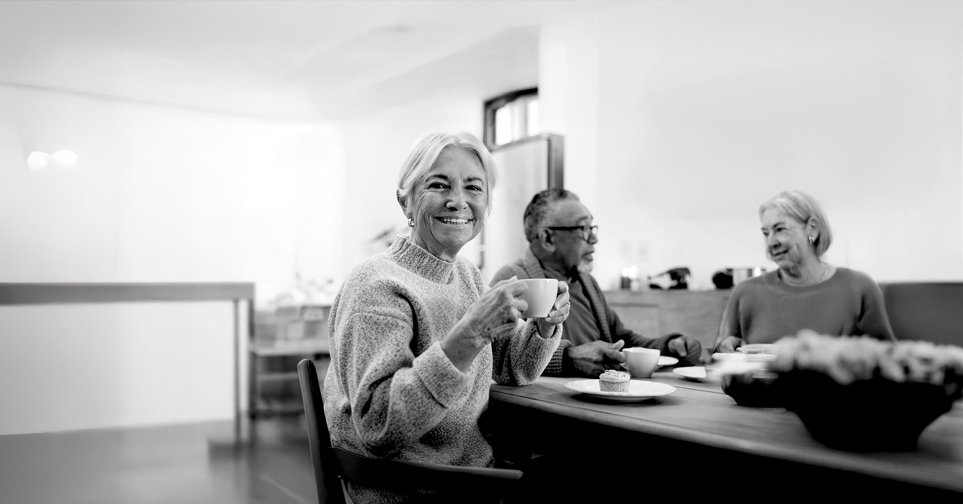 3 older adults sitting and visiting while having coffee at an open house